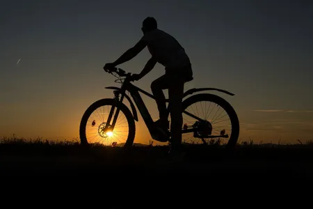 Radfahrende Person fährt durch den Sonnenuntergang