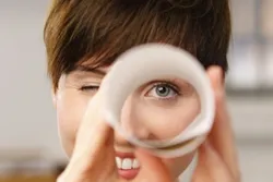 Quelle: contrastwerkstatt-stock.adobe.com lächelnde Frau schaut durch Fernglas aus gerolltem Papier